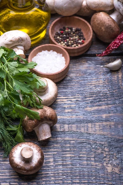 Mushrooms, parsley, dill, onion, olive oil, spices - ingredients for the preparation of mushroom dishes on the wooden background