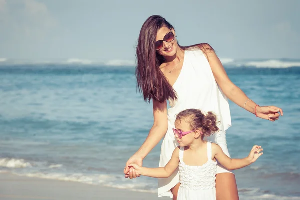 Mother and daughter playing on the beach at the day time.