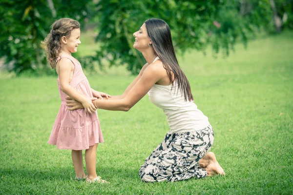 Mother and daughter playing on the grass at the day time.