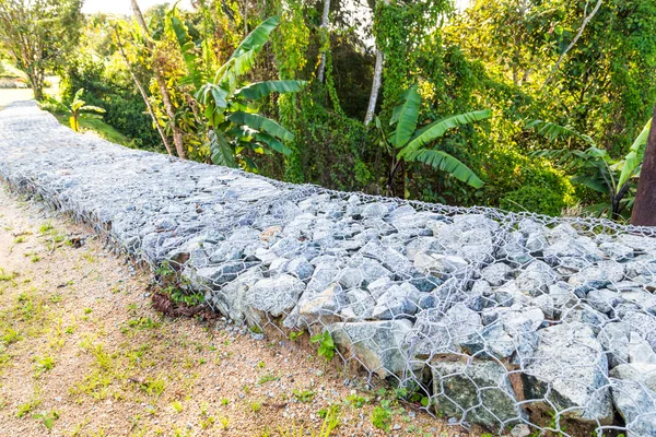 Slope earth retention wall with rocks and wire mesh cage