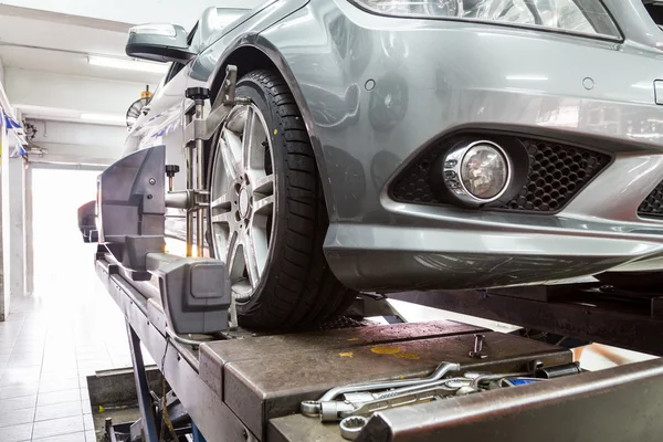 Closeup of tire clamped with aligner undergoing auto wheel alignment