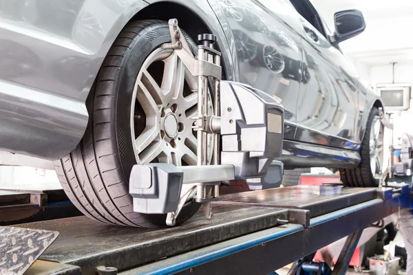 Closeup of tire clamped with aligner undergoing auto wheel alignment