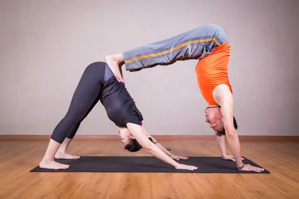 Partner yoga pose of double downward dog by a couple