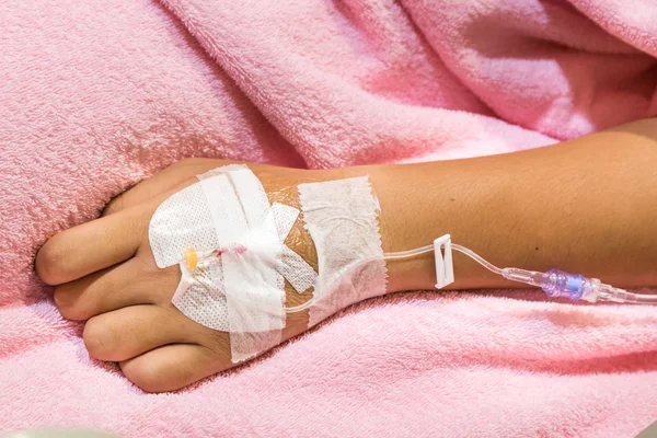 Patient hand in hospital with saline intravenous iv