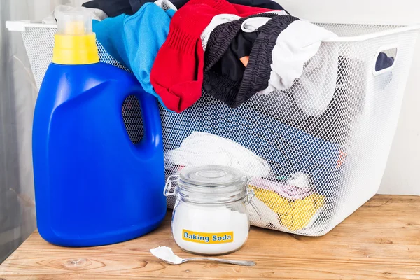 Baking soda with detergent and pile of dirty laundry.