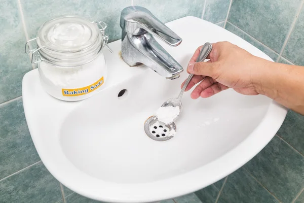 Baking soda poured to unclog drainage system at home.