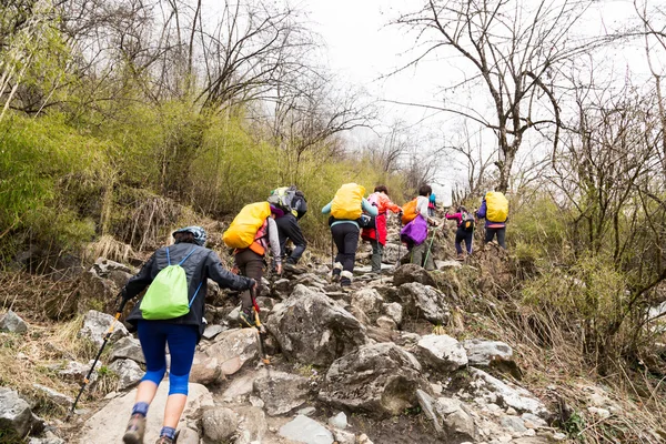 A group of people trekking an ascending rocky trail to the mountains