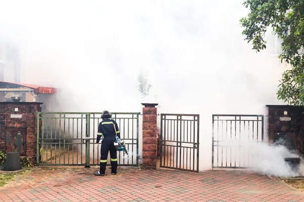 Worker fogging residential area with insecticides to kill aedes mosquitoes