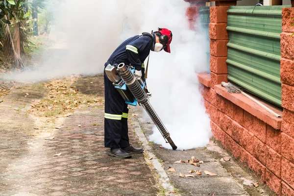 Worker fogging drain at residential area with insecticides to kill aedes mosquitoes, carrier of dengue virus