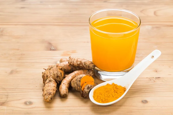 Healthy turmeric roots drinks in a transparent glass on wooden s