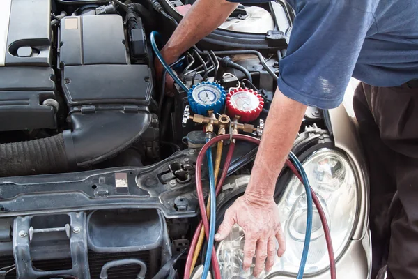 Mechanic with manometer inspecting auto vehicle air-condition co