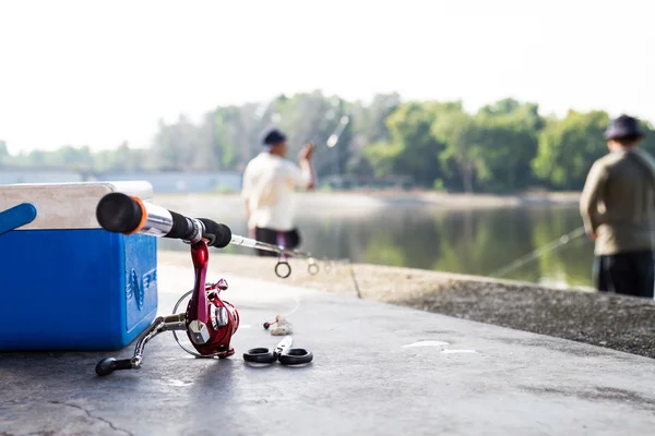 Fishing tools with background of men enjoying recreational fishing at a lake