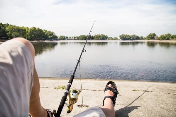 Man relaxing during recreational fishing at a lake on a beautiful morning