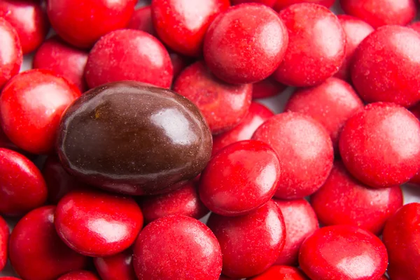 Focus on brown chocolate candy against heaps of red candies