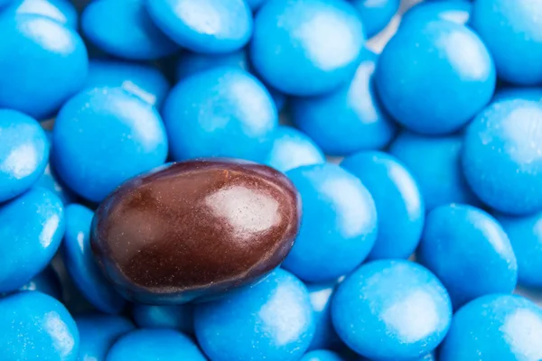 Focus on brown chocolate candy against heaps of blue candies
