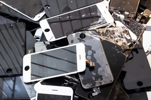 Stack of damaged smart phone body and cracked LCD screen