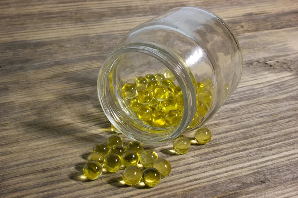 Cod fish oil gel capsules in glass jar on wooden background