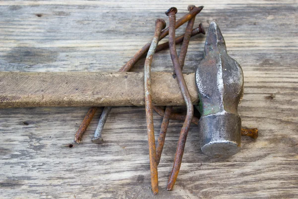 Old rusty nails and hammer on wooden background