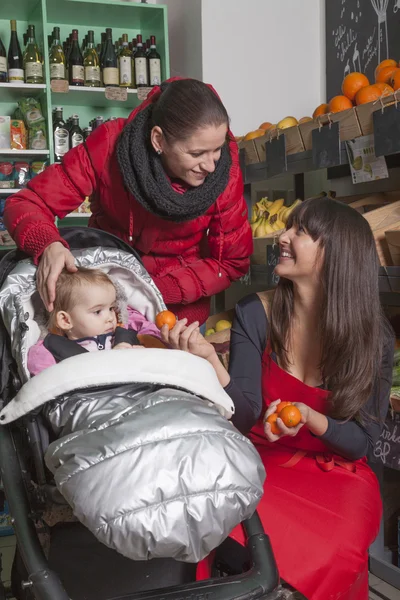 Mother toddler and shop assistant at a greengrocer