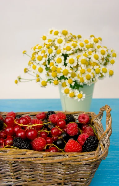 Mix of fresh berries in a basket on rustic wooden background