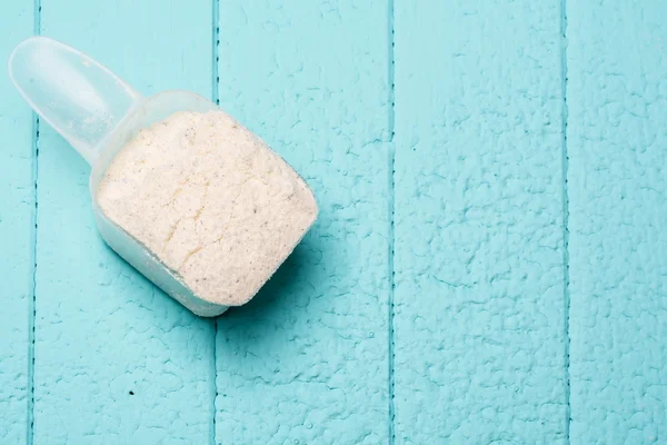 Container of milk whey protein. Close-up. Blue background