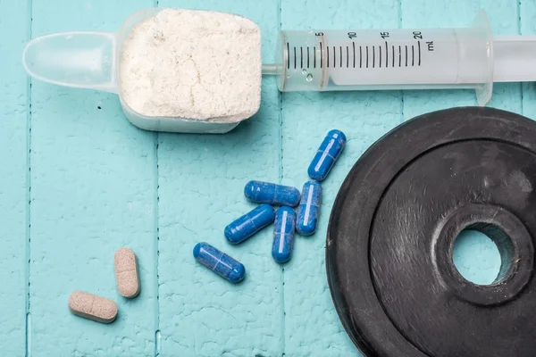 Container of milk whey protein, empty injection and pills. Close-up. Blue background