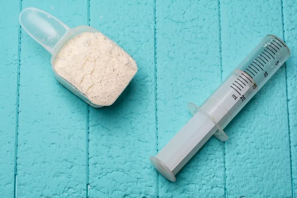 Container of milk whey protein and empty injection. Close-up. Blue background