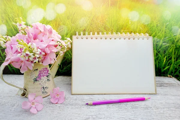 Blank page paper of calendar pencil and pink flower on wooden table in soft pastel tone of bokeh