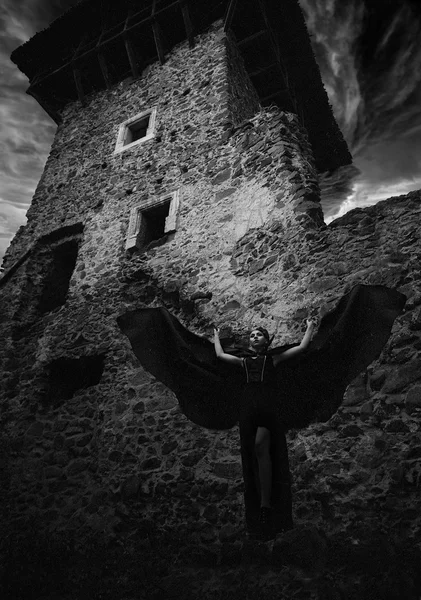 Dark queen of the ghost in the dark ruined castle, waving its wings on the background of the destruction of the tower of the castle, see the ruined castle walls
