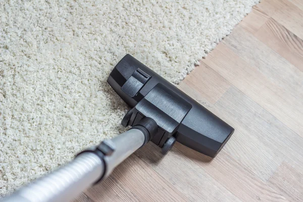 Vacuum cleaner being used to vacuum a carpet