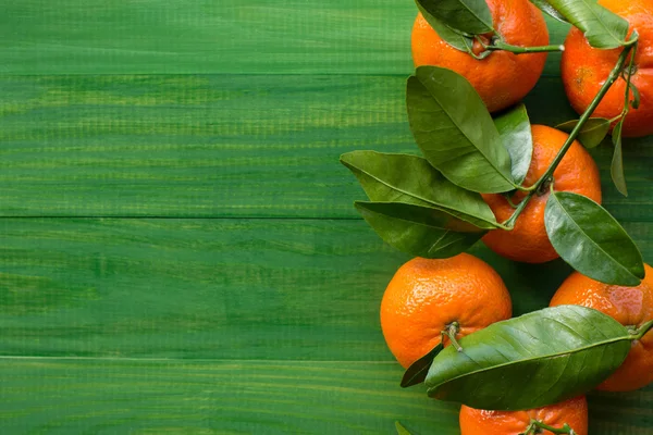 Fresh picked tangerine clementines on wooden green table. Bird eye view.