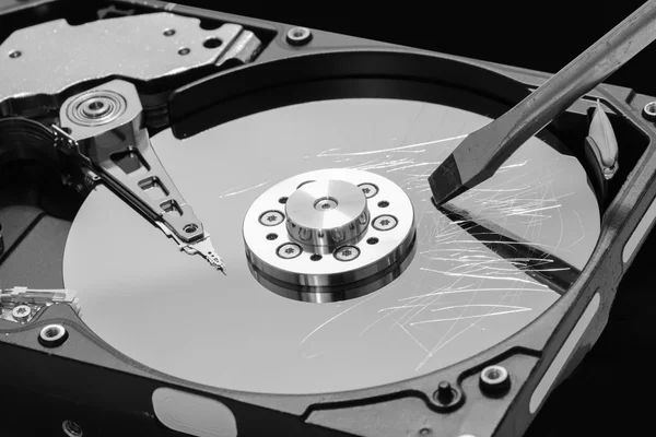 Screwdriver destroying a hard disk drive platter to erase the data