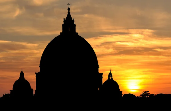 Silhouette of the huge domes of Saint Peters Basilica breaking the skyline at sunset in Vatican City, Rome