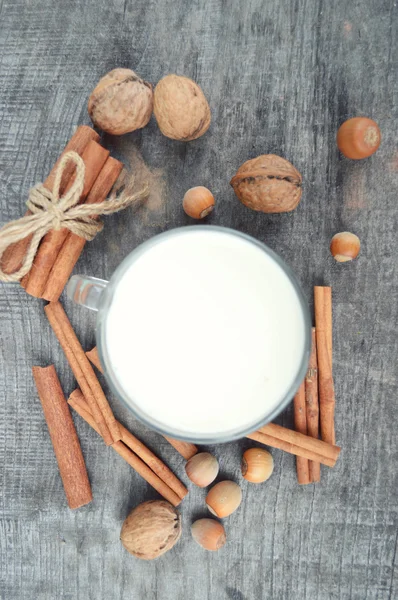 Cup of hot milk with cinnamon , Spices and hazelnuts, walnuts, closeup on wooden background