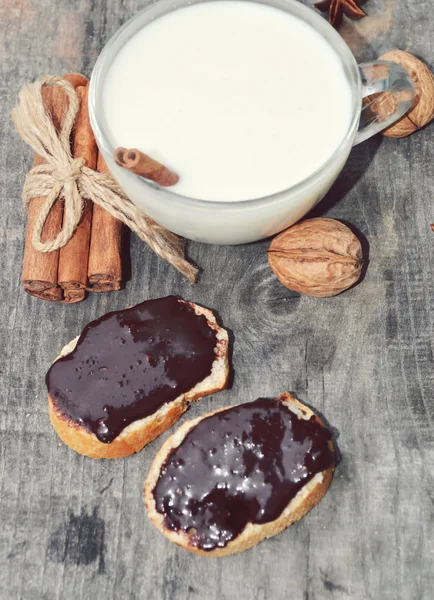 Cup of hot milk with cinnamon , Spices and hazelnuts, walnuts, closeup on wooden background