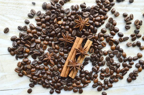 Bar of dark chocolate, milk chocolate bar, coffee beans, star anise, cinnamon sticks, seasonings, spices, close-up on a white wooden background