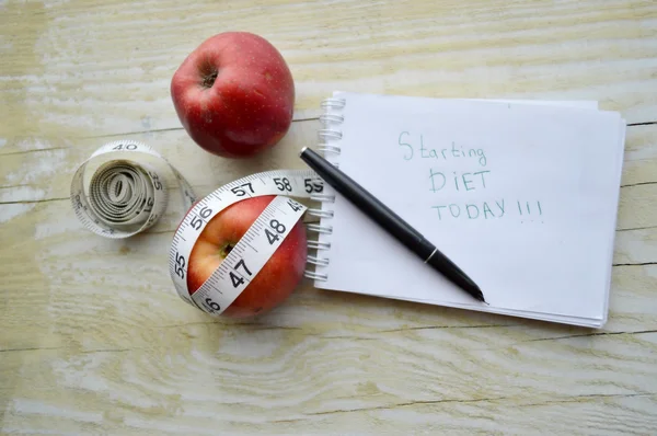 Notebook, two apples, pen and measuring tape