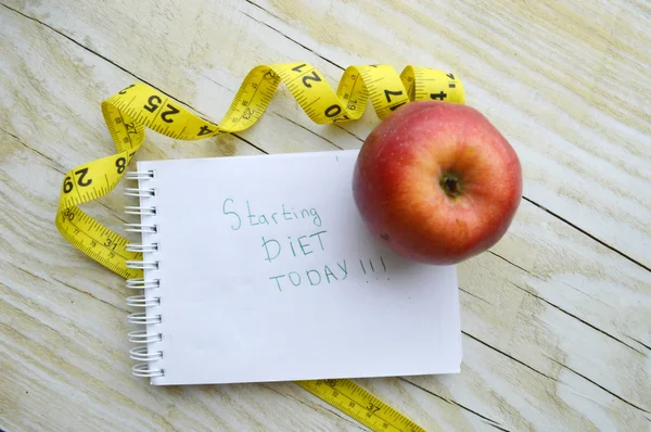 Notebook with measuring tape and an apple
