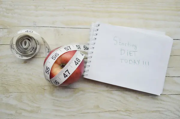 Notebook with measuring tape and an apple