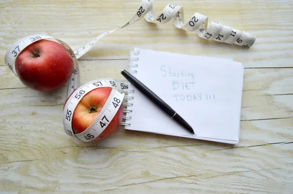Notebook with measuring tape and two apples