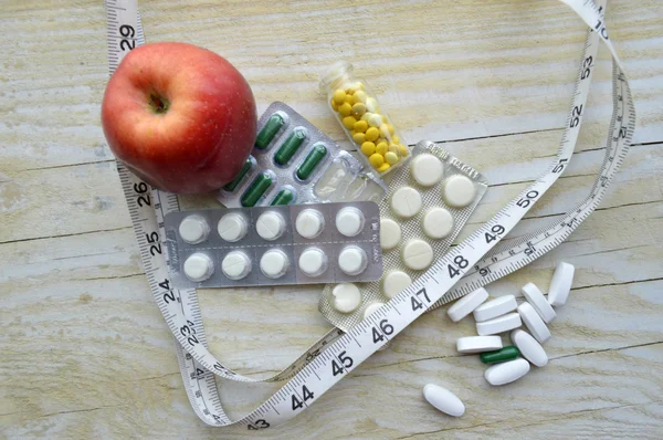 Measuring tape with pills and apple