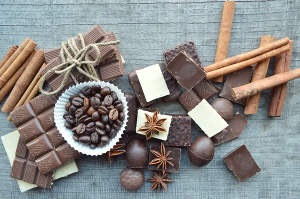 Bar of chocolate, coffee beans, hazelnuts, walnuts, cinnamon, coriander, spices .chocolate bar, candy bars,  different chocolate sweets on a wooden background