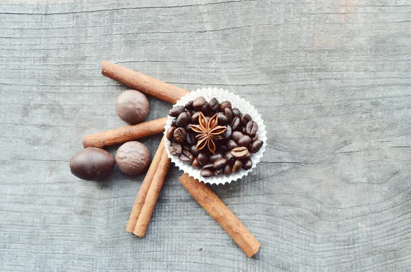 Bar of chocolate, coffee beans, hazelnuts, walnuts, cinnamon, coriander, spices .chocolate bar, candy bars,  different chocolate sweets on a wooden background