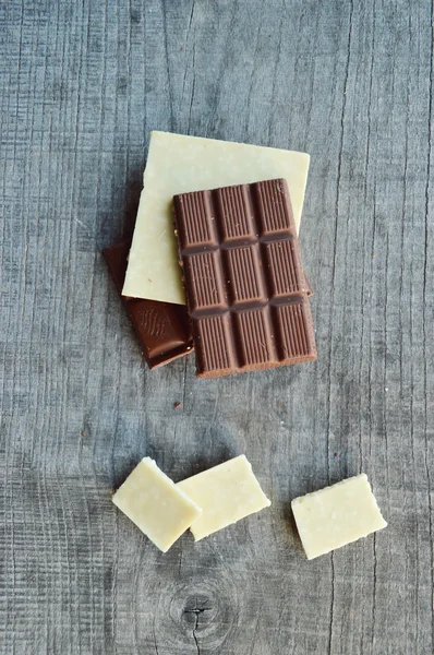 Bar of chocolate, coffee beans, hazelnuts, walnuts, cinnamon, coriander, spices .chocolate bar, candy bars,  different chocolate sweets on a wooden background