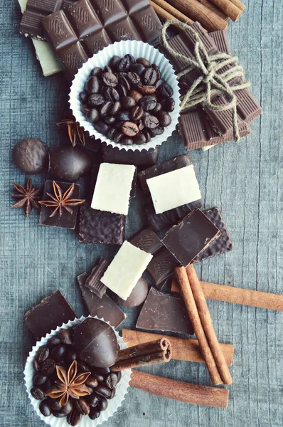 Bar of chocolate, coffee beans, hazelnuts, walnuts, cinnamon, coriander, spices .chocolate bar, candy bars,  different chocolate sweets on a wooden background