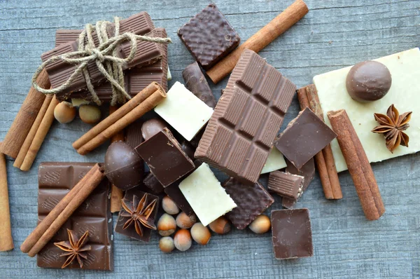 Bar of chocolate, coffee beans, hazelnuts, walnuts, cinnamon, coriander, spices .chocolate bar, candy bars,  different chocolate sweets on a wooden background.big choice of various sweets