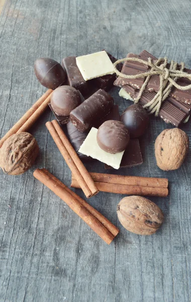 Bar of chocolate, coffee beans, hazelnuts, walnuts, cinnamon, coriander, spices .chocolate bar, candy bars,  different chocolate sweets on a wooden background.big choice of various sweets