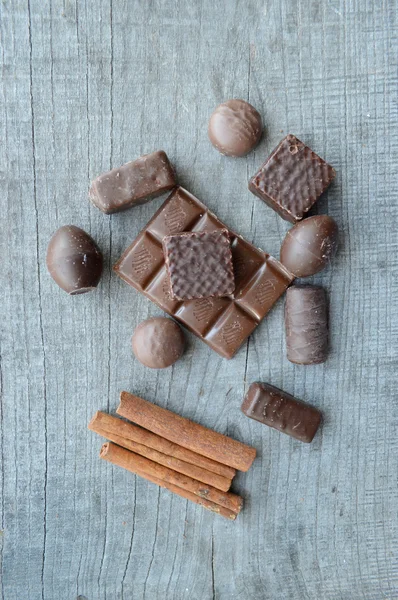 Bar of chocolate, coffee beans, hazelnuts, walnuts, cinnamon, coriander, spices .chocolate bar, candy bars,  different chocolate sweets on a wooden background.big choice of various sweets