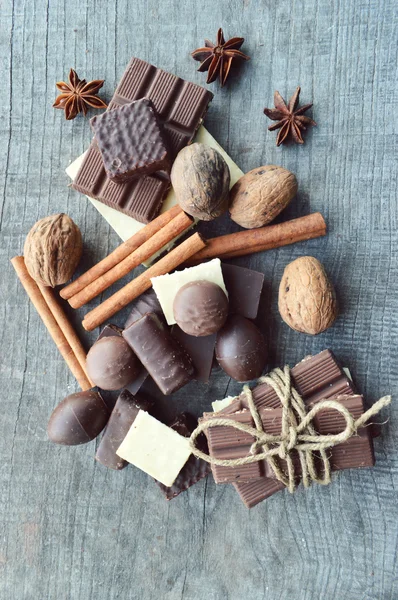 Bar of chocolate, coffee beans, hazelnuts, walnuts, cinnamon, coriander, spices .chocolate bar, candy bars,  different chocolate sweets on a wooden background.big choice of various sweets