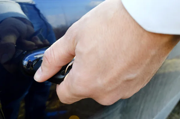 Male hand with car keys opening car door